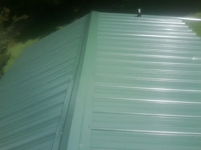 New green metal panels meeting at the ridge of a roof — Flat Roof Repair work by our crew in New Plymouth