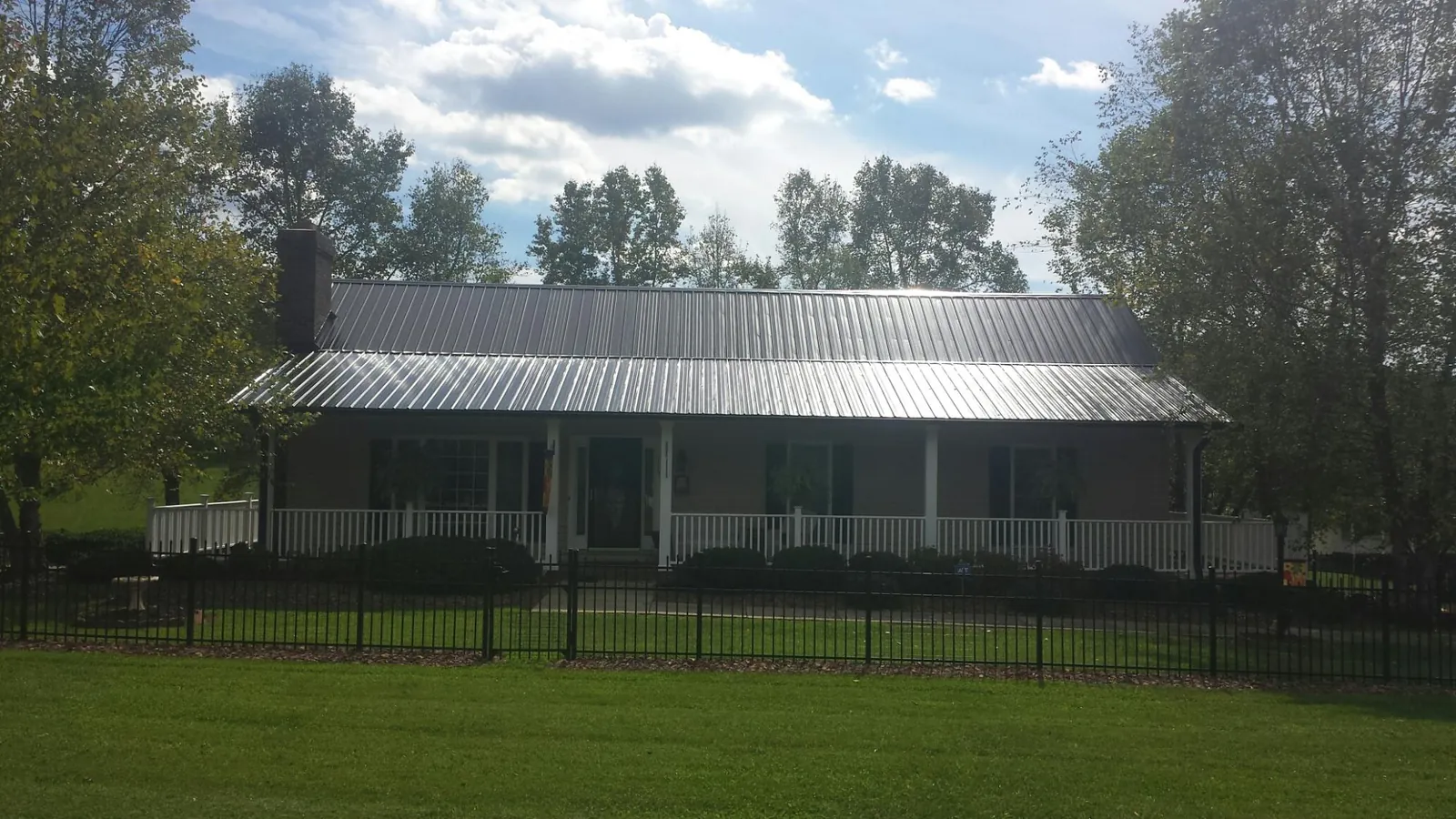 Gray metal roof on a brick ranch with a full width front porch — Gutter Guard Installation work by our crew in New Plymouth