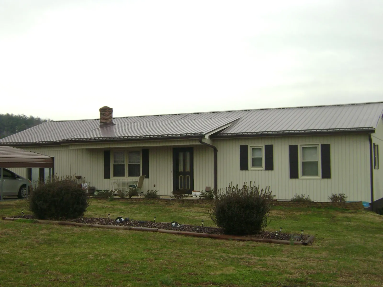 Brown metal roof on a cream sided ranch home with a brick chimney in New Plymouth