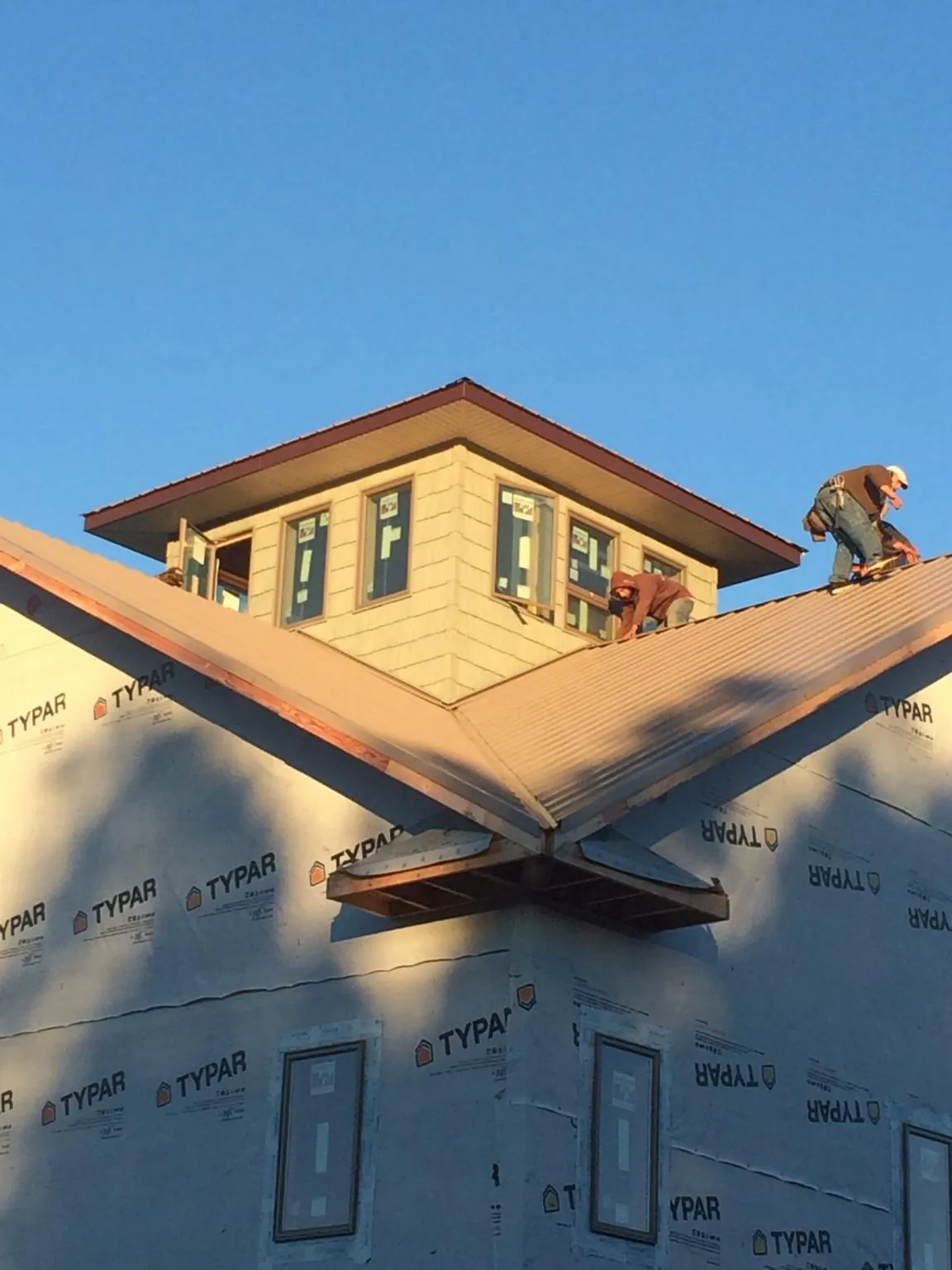 Roofers working around a rooftop cupola on a new metal roof at sunset — Roof Waterproofing in New Plymouth by Roofing Brothers